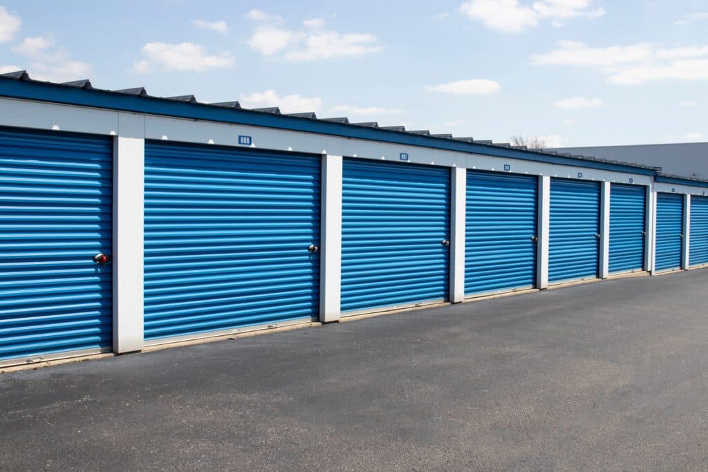 Blue self-storage units labeled 'Keypers Storage' arranged in a parking lot under clear skies.